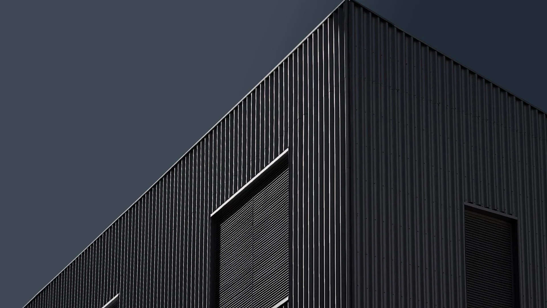 Dark aluminum batten facade catching raking light
